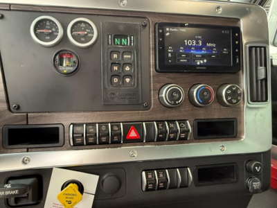 Cab panel of a Western Star 47X truck showing gauges, gear selector, digital radio display, climate controls, and hazard switch.