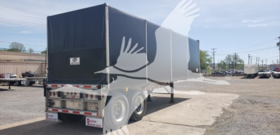 Trailer rear and side view showing curtainside Big Bubba with dual rear axles and white reflective tape, yard in background.