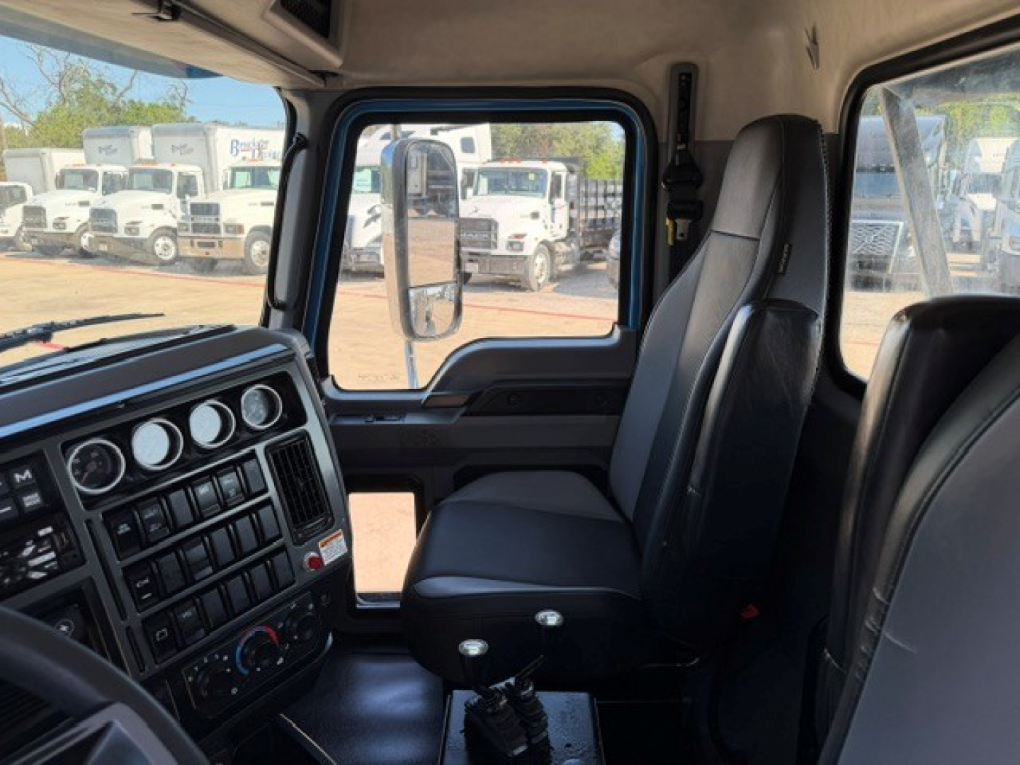 Cab interior of a 2021 Mack GR64B rolloff truck showing driver's seat and dashboard with multiple gauges and controls.