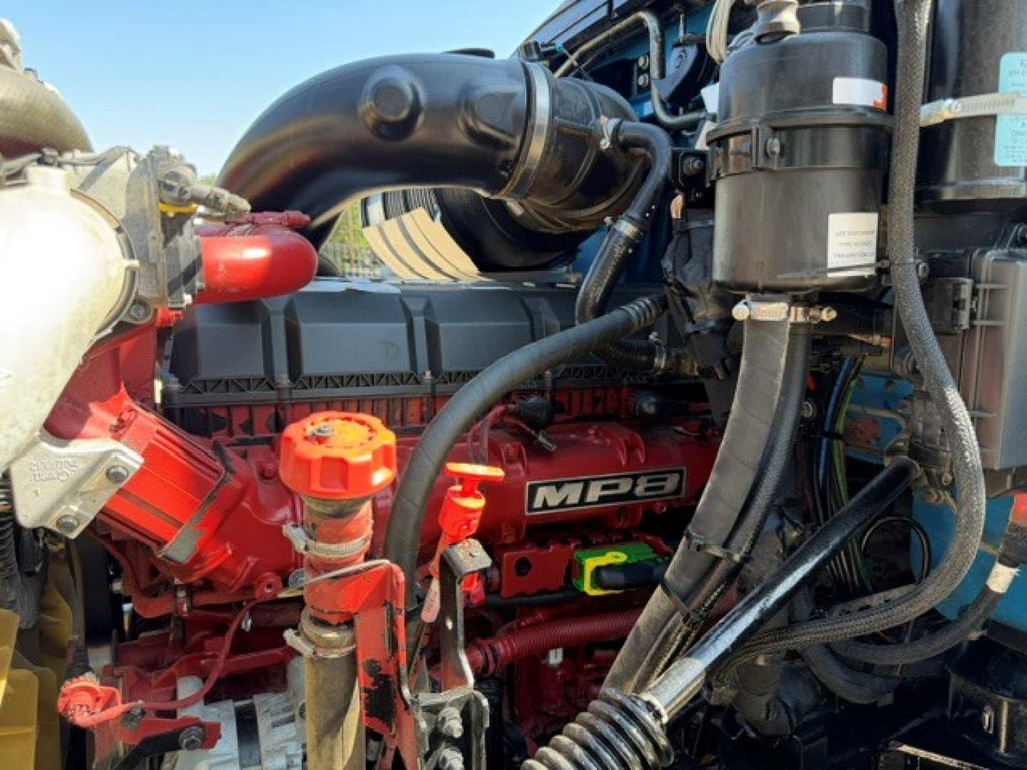 Engine bay of Mack GR64B showing MP8 engine and various hoses and components.