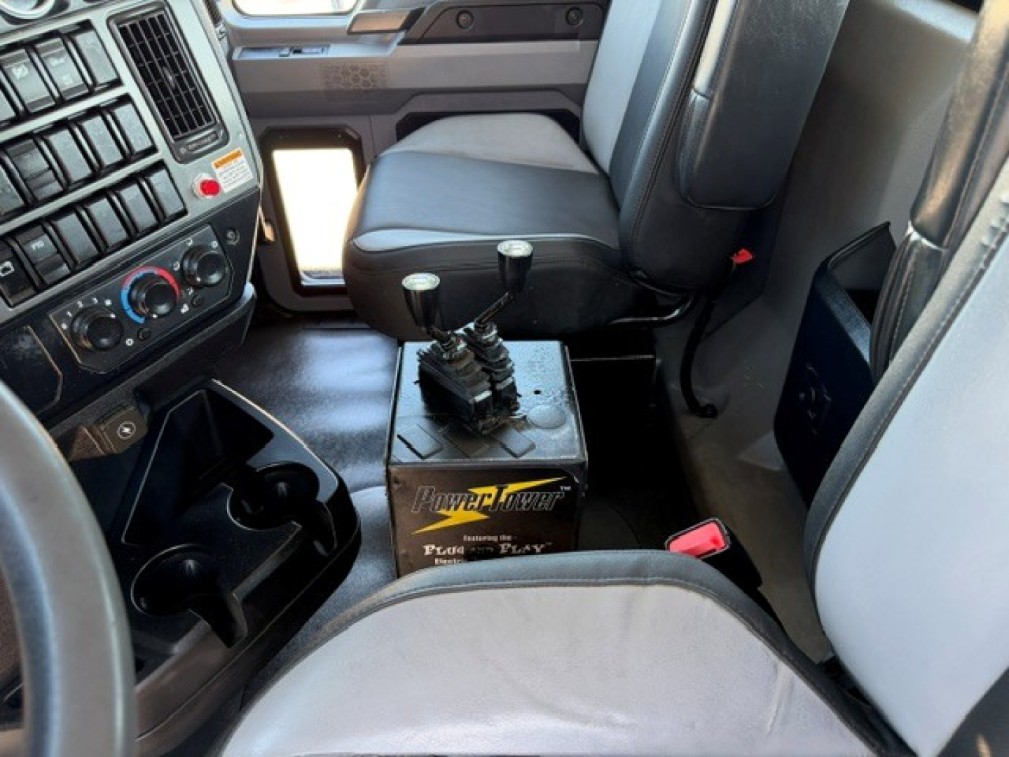 Cab interior of a 2021 Mack GR64B rolloff truck showing shifter on a pedestal, gear lever with multiple stalks, driver seat, and dashboard controls.