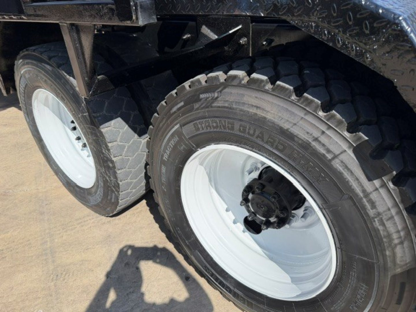 Mack GR64B truck rear dual wheels showing white rims and heavy-duty tires in service environment.