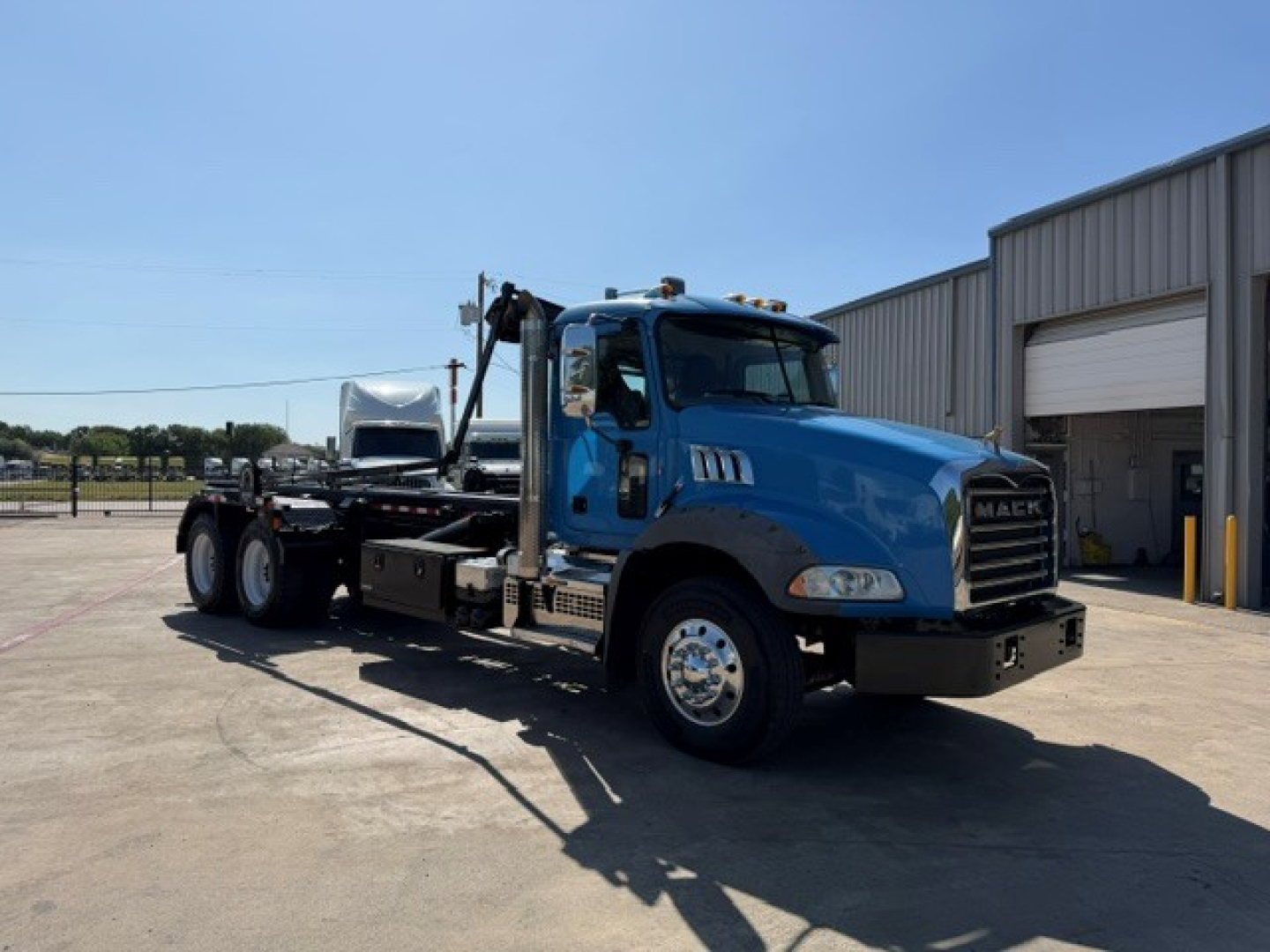 Mack GR64B roll-off truck in blue, side view, with cab and chassis, no visible license plate.
