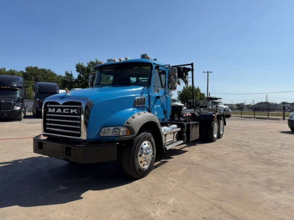 Blue 2021 Mack GR64B truck with flatbed chassis, front view showing Mack grille, headlights, and large bumper.