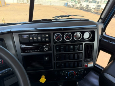 Dashboard of a 2021 Mack GR64B cab showing gear selector R N D M and multiple gauges; HVAC controls and radio panel visible.