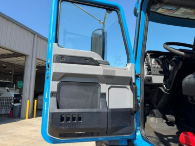 Truck cab door interior of a 2021 Mack GR64B, blue exterior, open door showing door panel and cockpit with steering wheel and controls.
