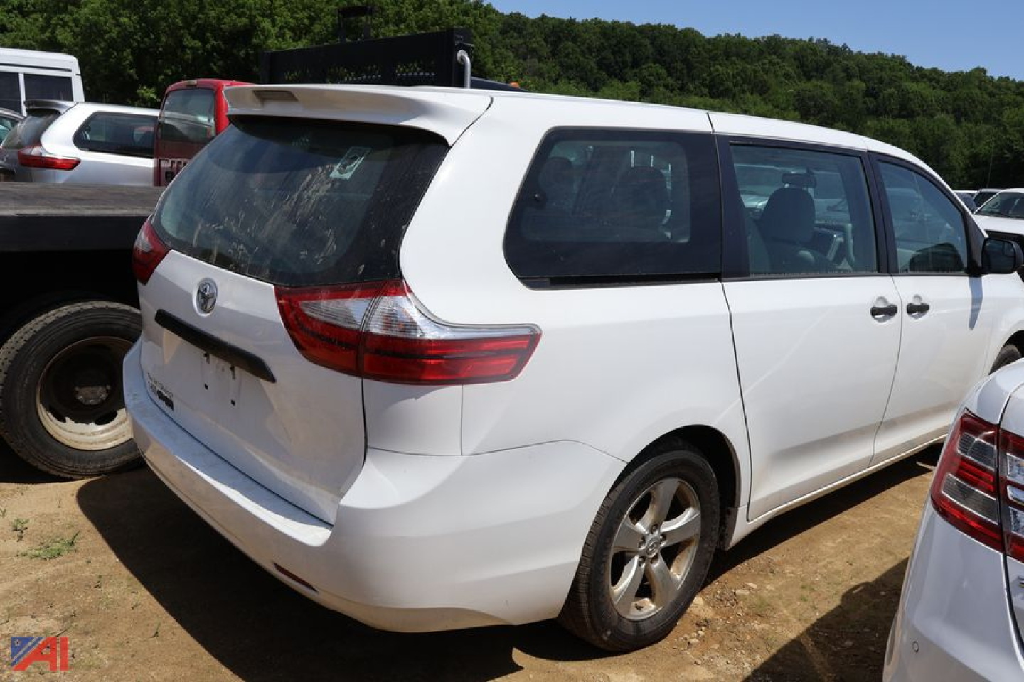 Toyota Sienna minivan rear-left view showing tailgate and taillights in a used vehicle lot.