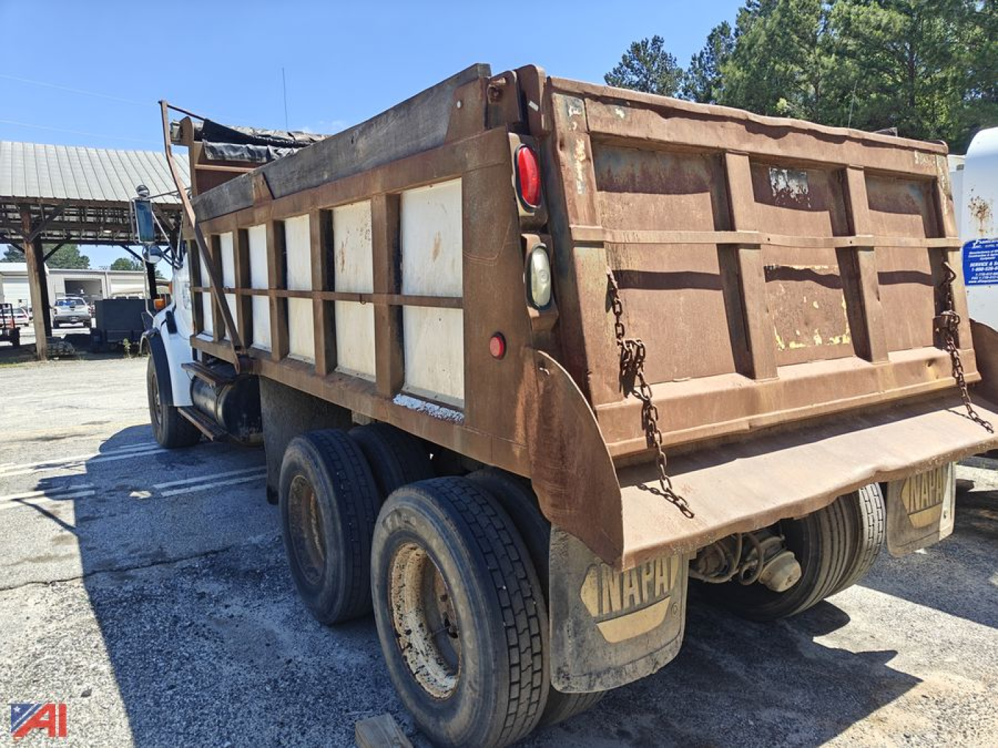 Dump truck rear view showing bed and dual rear wheels, rusty side panels, and tailgate chains on a Sterling LT9500 Series dump truck.