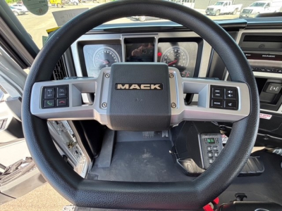 Steering wheel of a 2026 Mack MD7 showing the Mack logo and control stalks on both sides, instrument cluster in the background.