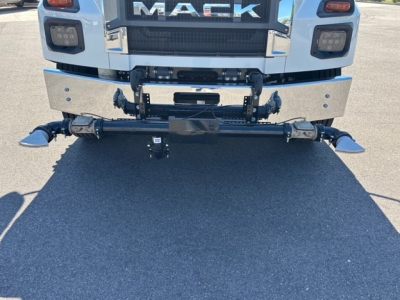 Front view of a white Mack MD7 truck showing heavy-duty chrome bumper and hitch assembly with winch and mounting brackets.
