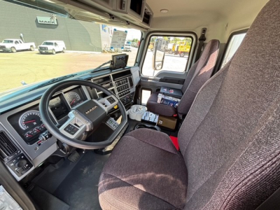 Interior of a 2026 Mack MD7 truck cab, steering wheel, dashboard, and front seats visible; text on the dash includes gauges and control panels.
