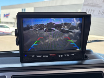 Monitor displaying rearview camera guidelines in a Mack MD7 truck cabin; the screen shows colored lines (green, yellow, red) for parking assist.