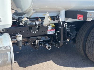 Mack MD7 truck chassis showing suspension, linkage, and fuel tank area with warning labels and connectors visible.