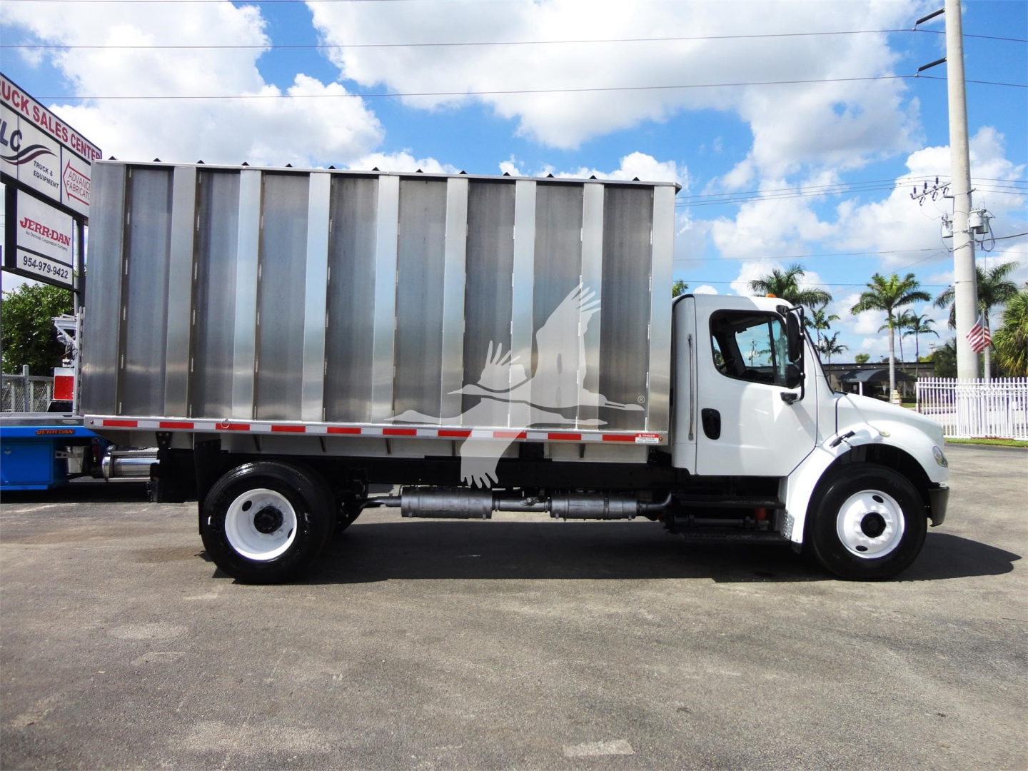 Side view of a 2014 Freightliner M2 106 box truck with a large metal cargo area, white cab, black chassis, and a bird silhouette graphic on the cargo box.