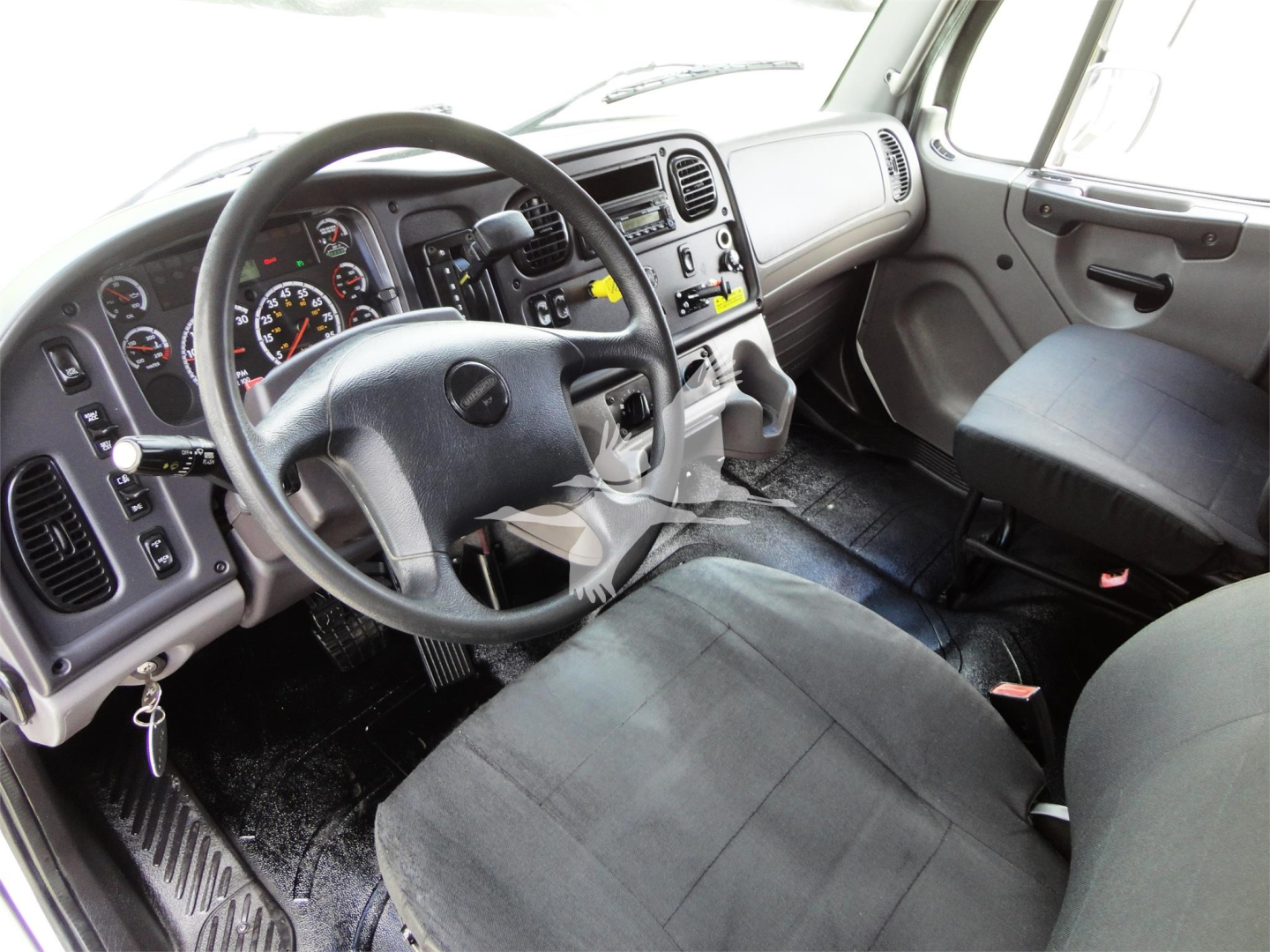 Truck cab interior of a 2014 Freightliner M2 106 showing steering wheel, dashboard with gauges, and front seats.