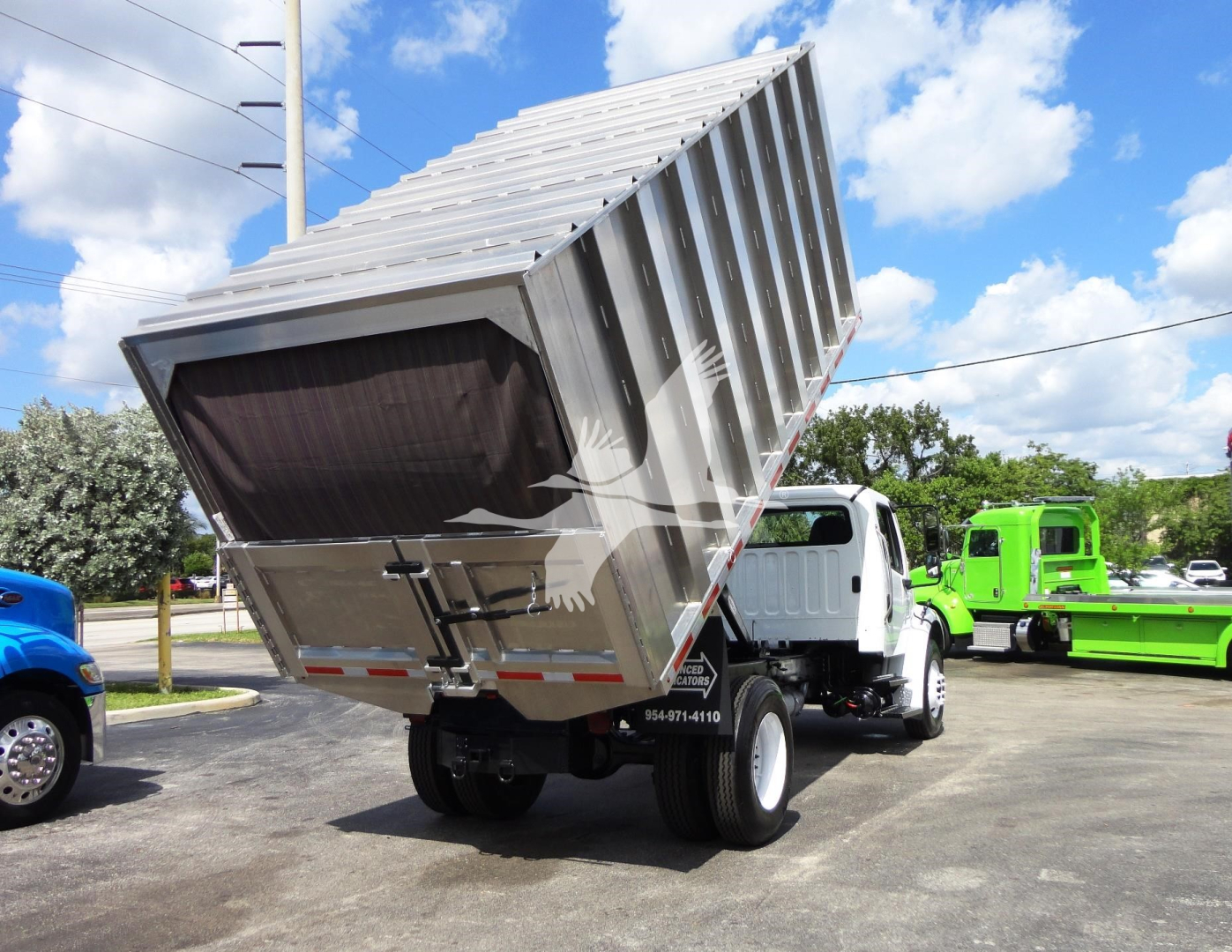 Dump bed Freightliner M2 106 dump truck in raised position showing cargo bed and rear wheels.