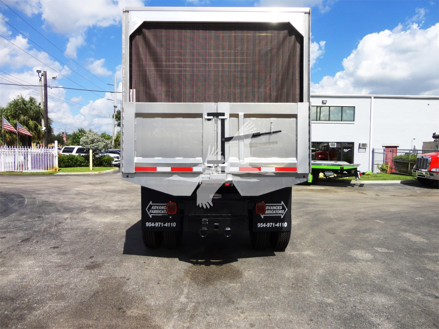 Rear view of a Freightliner M2 106 dump truck with tailgate closed and a tarp-covered bed.