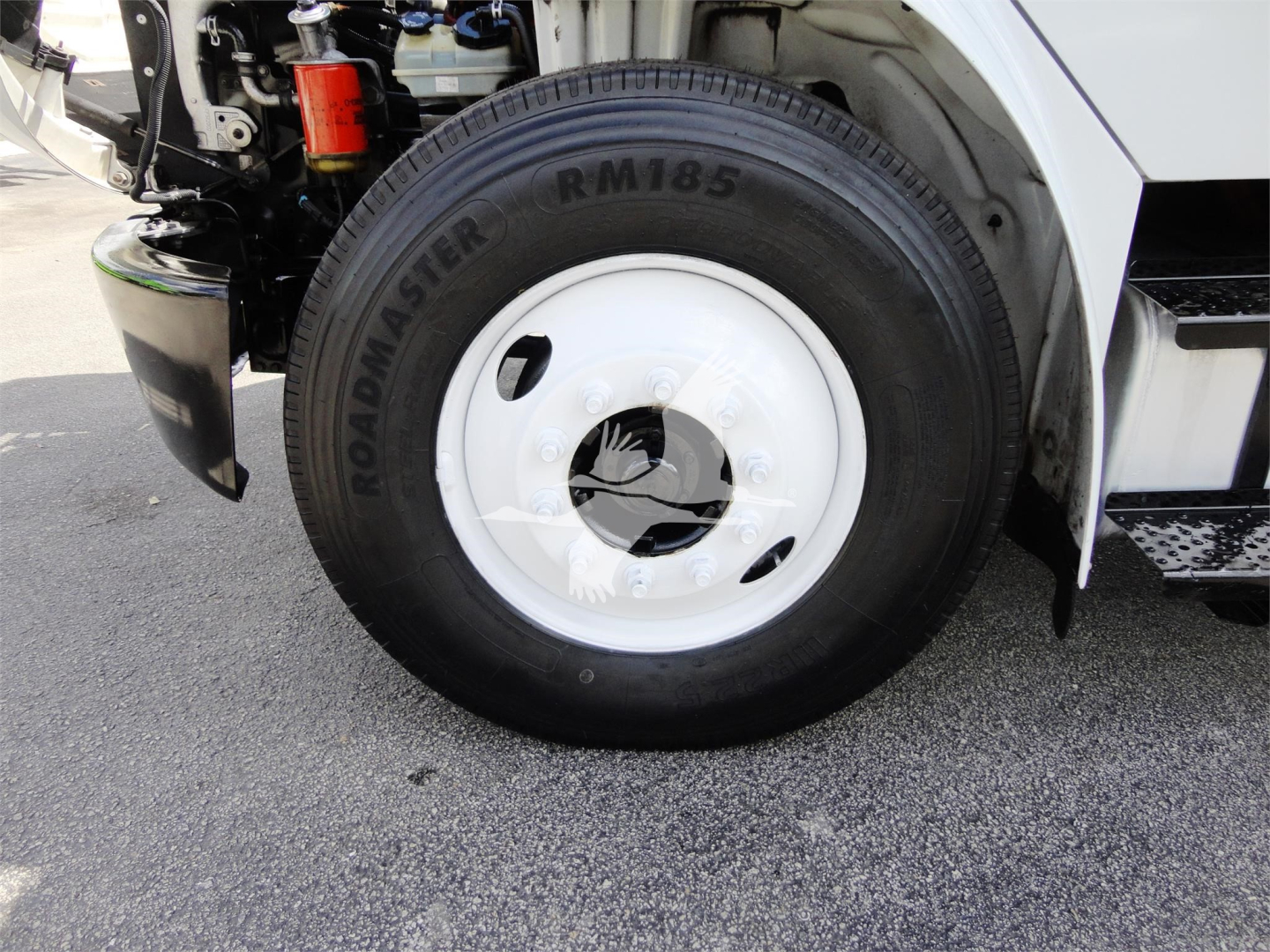 Wheel and front suspension of a 2014 Freightliner M2 106 showing RM85 Roadmaster tire and white steel wheel.