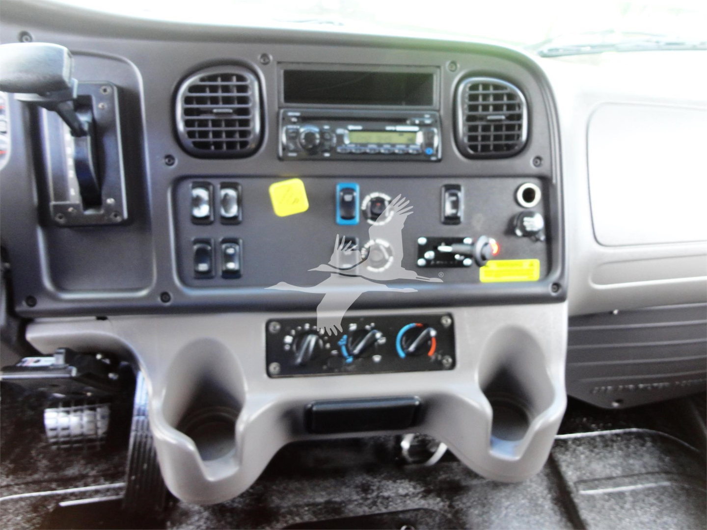 Dashboard of a Freightliner M2 truck showing radio, climate controls, and various switches labeled with colored markers.