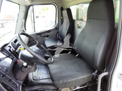 Cab interior of a Freightliner M2 106 truck showing driver seat, passenger seat, steering wheel, dashboard, and door window.
