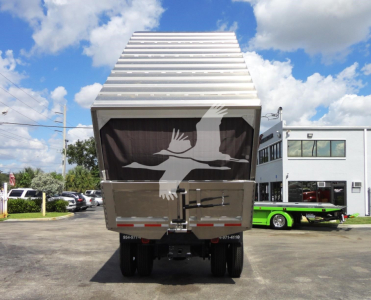 Rear view of a 2014 Freightliner M2 106 dump truck with aluminum dump bed raised, showing tailgate, taillights, and rear bumper.