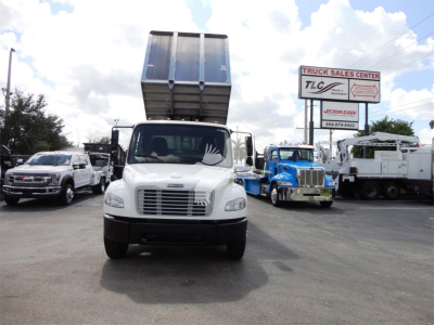 Front view of a 2014 Freightliner M2 106 dump truck with raised bed in a dealership lot, other trucks visible in background.