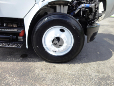 Fleet truck front wheel and cab area showing wheel hub and tire with engine bay visible.