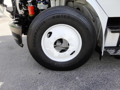 Wheel and front suspension of a 2014 Freightliner M2 106 showing RM85 Roadmaster tire and white steel wheel.