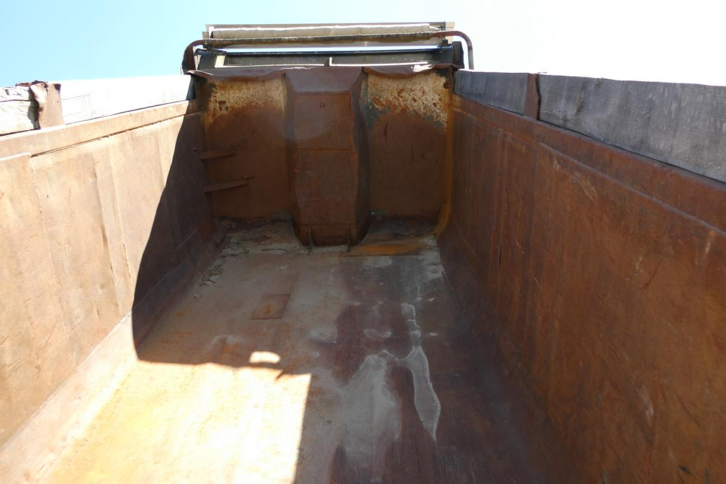 Mack RD690S dump truck bed interior showing rusted side walls and bucket with sunlight on floor.