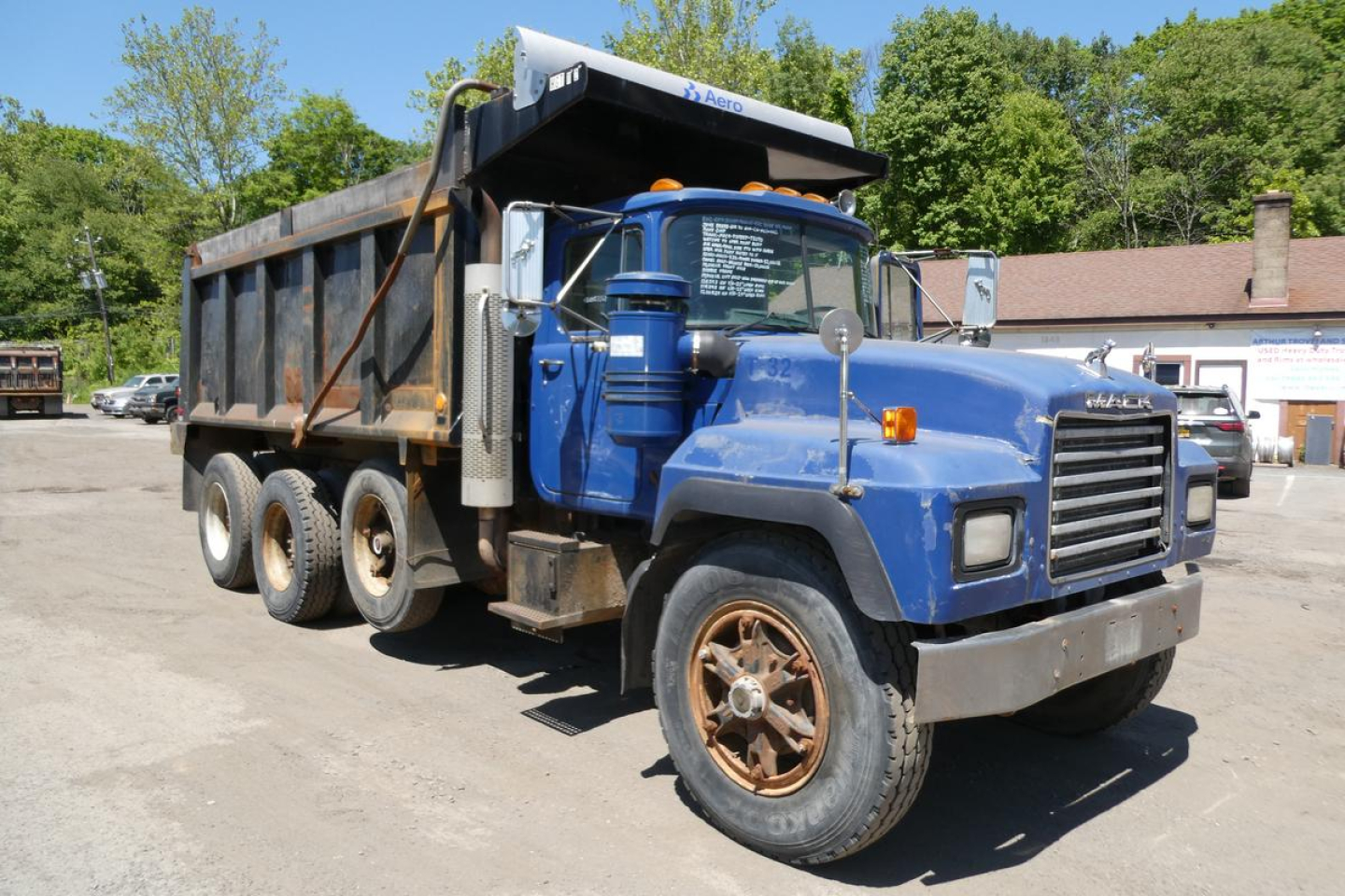 Mack RD690S dump truck showing side view with blue cab and black dump body.