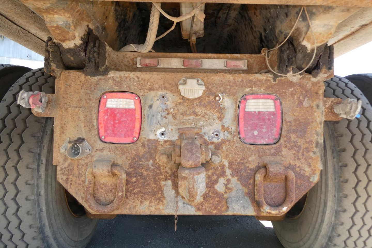 Mack RD690S dump truck rear view showing rusty chassis, taillights, and hitch area with wear marks.