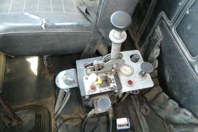 Cockpit panel with joystick shift lever and multiple gauges in a Mack RD690S cab interior showing control console and levers.