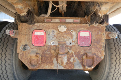 Mack RD690S dump truck rear view showing rusty chassis, taillights, and hitch area with wear marks.