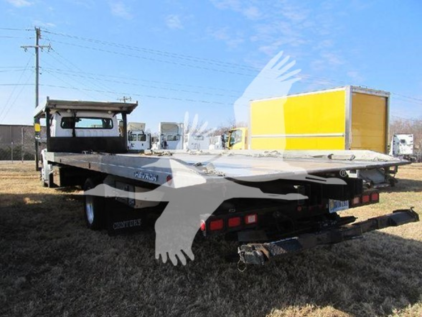 2019 Freightliner M2 106 auto carrier truck rear view showing flatbed and bumper, with yellow and white box in background.