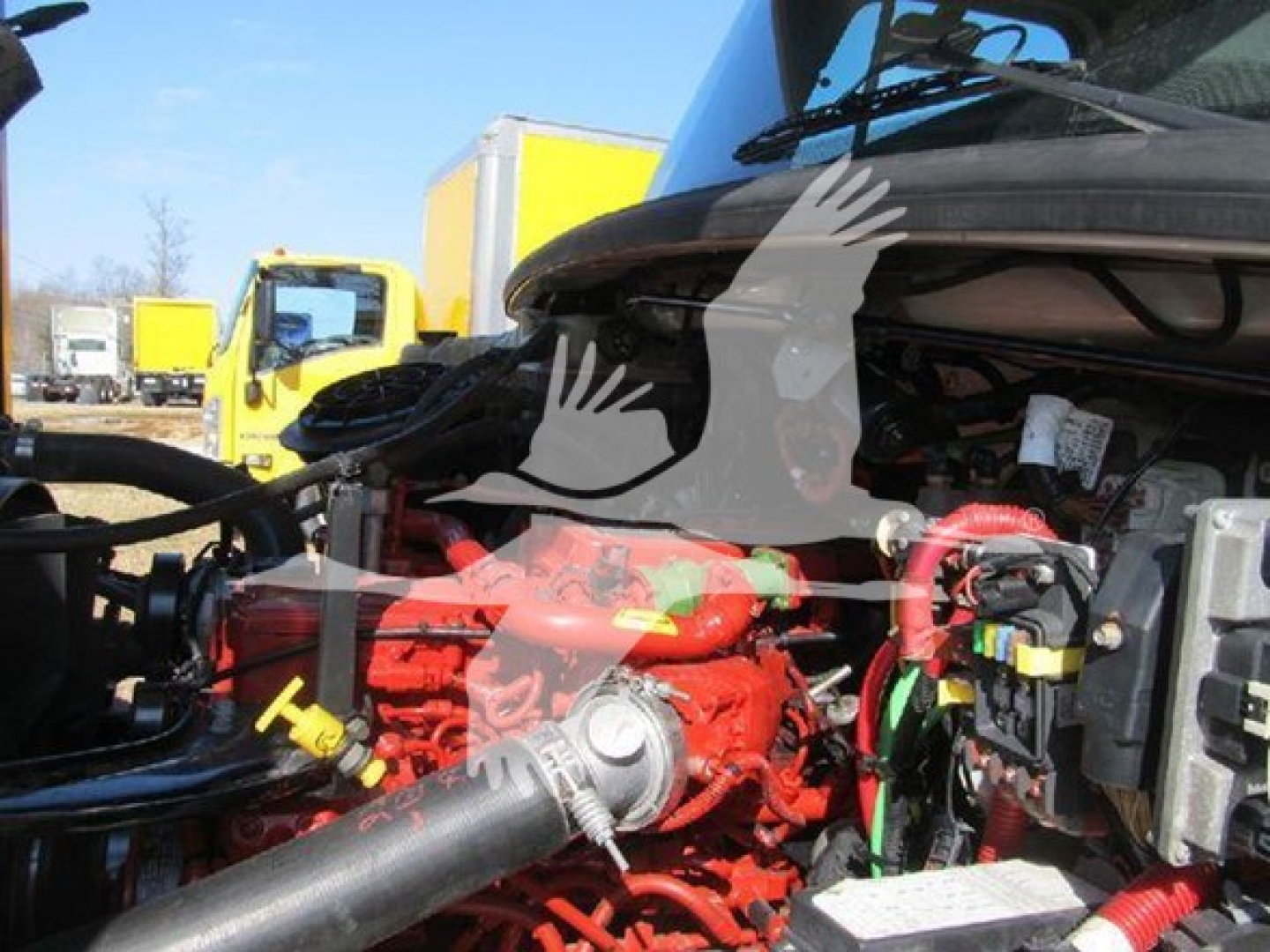 Freightliner M2 106 engine bay showing red engine block and various hoses with a yellow truck in background