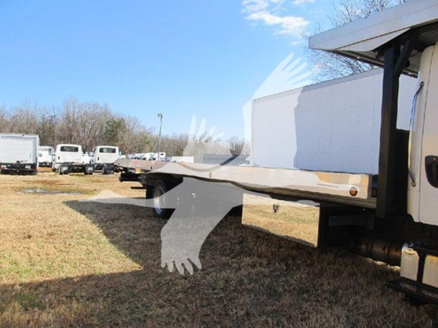 Flatbed truck bed extended from Freightliner M2 106 with white cab, side view showing cargo deck and rear tires.