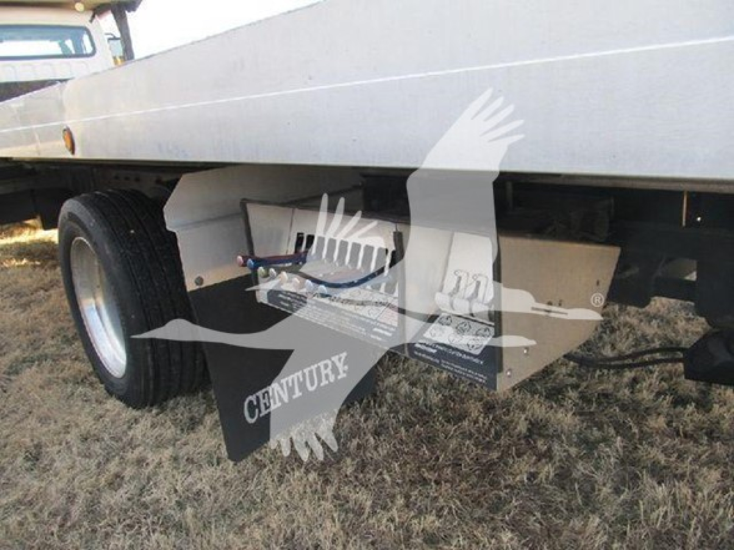 Suspended undercarriage of a Freightliner M2 106 auto carrier showing the trailer deck and dual rear wheels.