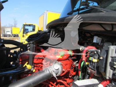 Freightliner M2 106 engine bay showing red engine block and various hoses with a yellow truck in background