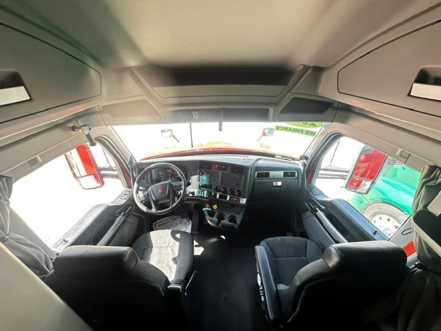 Kenworth T680 cab interior showing steering wheel and dashboard view from front seats.