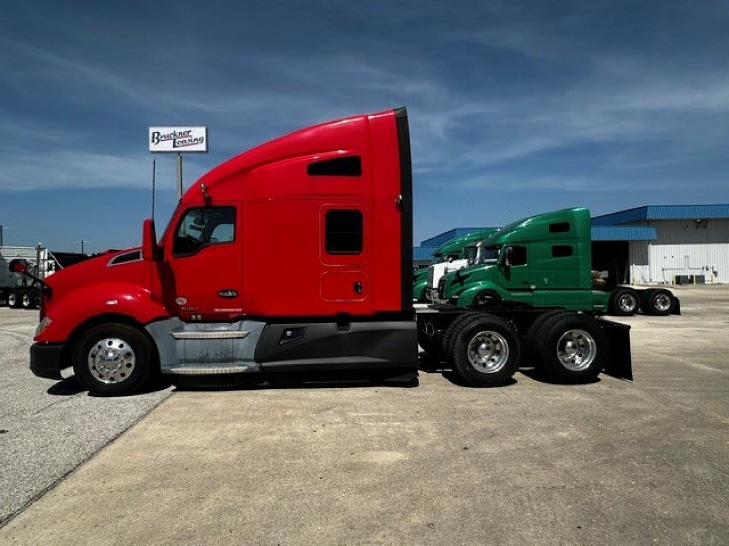 Kenworth T680 sleeper tractor in red with green trailer in lot, side view, VIN 3WKYD49X4NF137385 visible on listing.