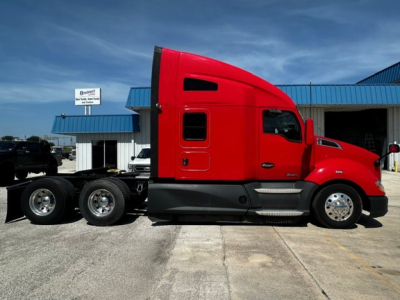 Kenworth T680 tractor-side view showing red cab and dual rear axles