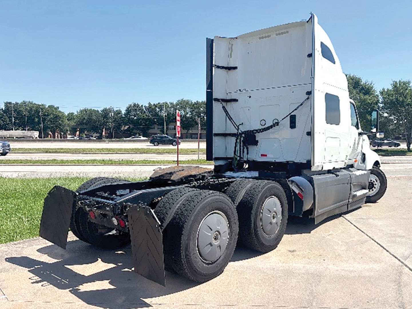 Tractor trailer rear view showing LT625 cab and 3-axle configuration with fifth wheel removed and mud flaps.
