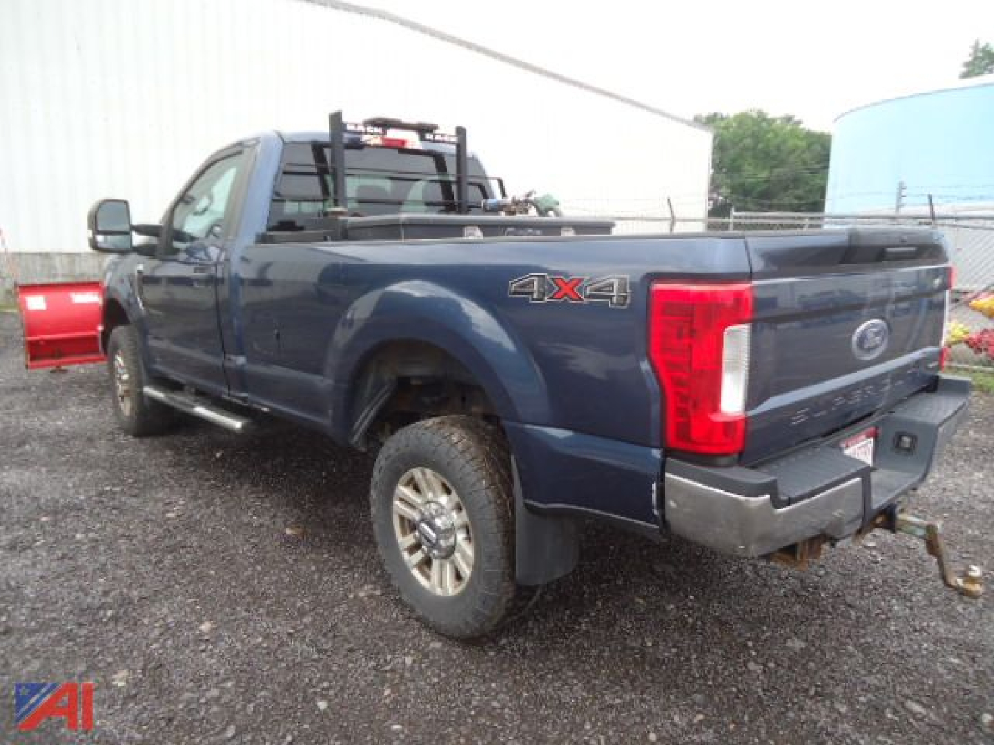 Ford F-350XLT Super Duty pickup with 4x4 emblem, crew cab long bed, towing hitch, plow mount and high-visibility red plow in background; blue exterior