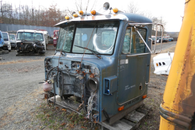 Cab section of a blue 1988 Peterbilt 377 truck showing front with exposed wiring and missing grille. Side mirrors, roof lights, and weathered body panels visible.