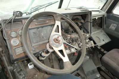 Cab interior with steering wheel and dashboard showing gauges and wiring in a used Peterbilt 377 truck.