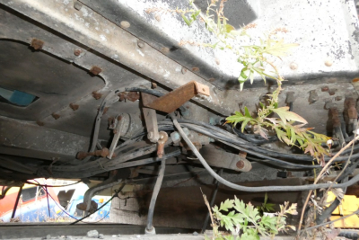 Underbody view of a Peterbilt truck chassis with tangled cables and rusted hardware.