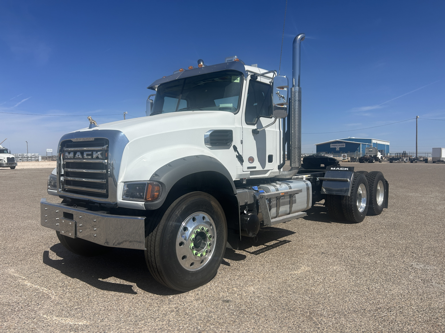 White 2027 Mack GR64FT conventional daycab tractor in a parking lot showing front grille and dual rear axles.