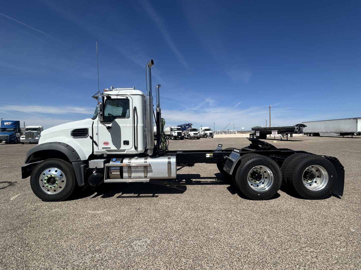 Mack GR64FT tractor cab side view showing front axle, two rear axles, exhaust stack, fuel tanks, and chassis with no trailer attached.