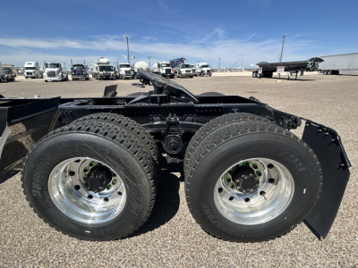 Dual rear axle setup with polished aluminum wheels and dual tires on a Mack truck chassis; chassis rails and mounting hardware visible.