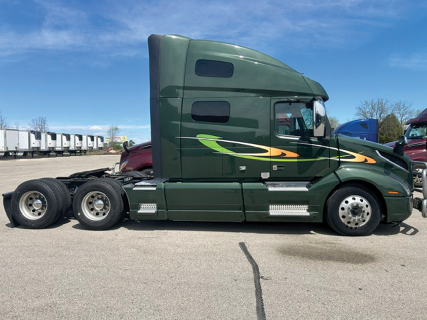 Volvo VNL 760 sleeper cab truck side view showing green with yellow-green stripe, two axles, fuel tanks, and aerodynamic fairings.